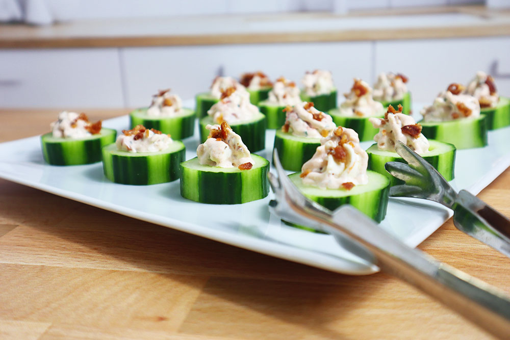 Image of our Bacon, Cucumber, and Tomato Finger Sandwiches on a plater in a kitchen