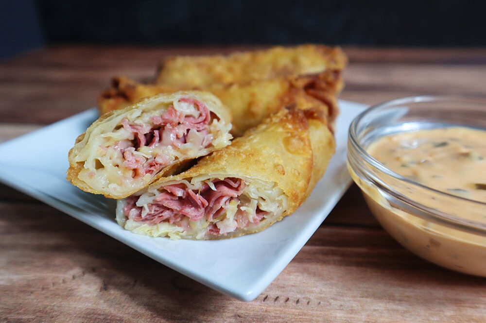 Image of our Reuben Egg Roll recipe on a white plate and served with thousand island dipping sauce